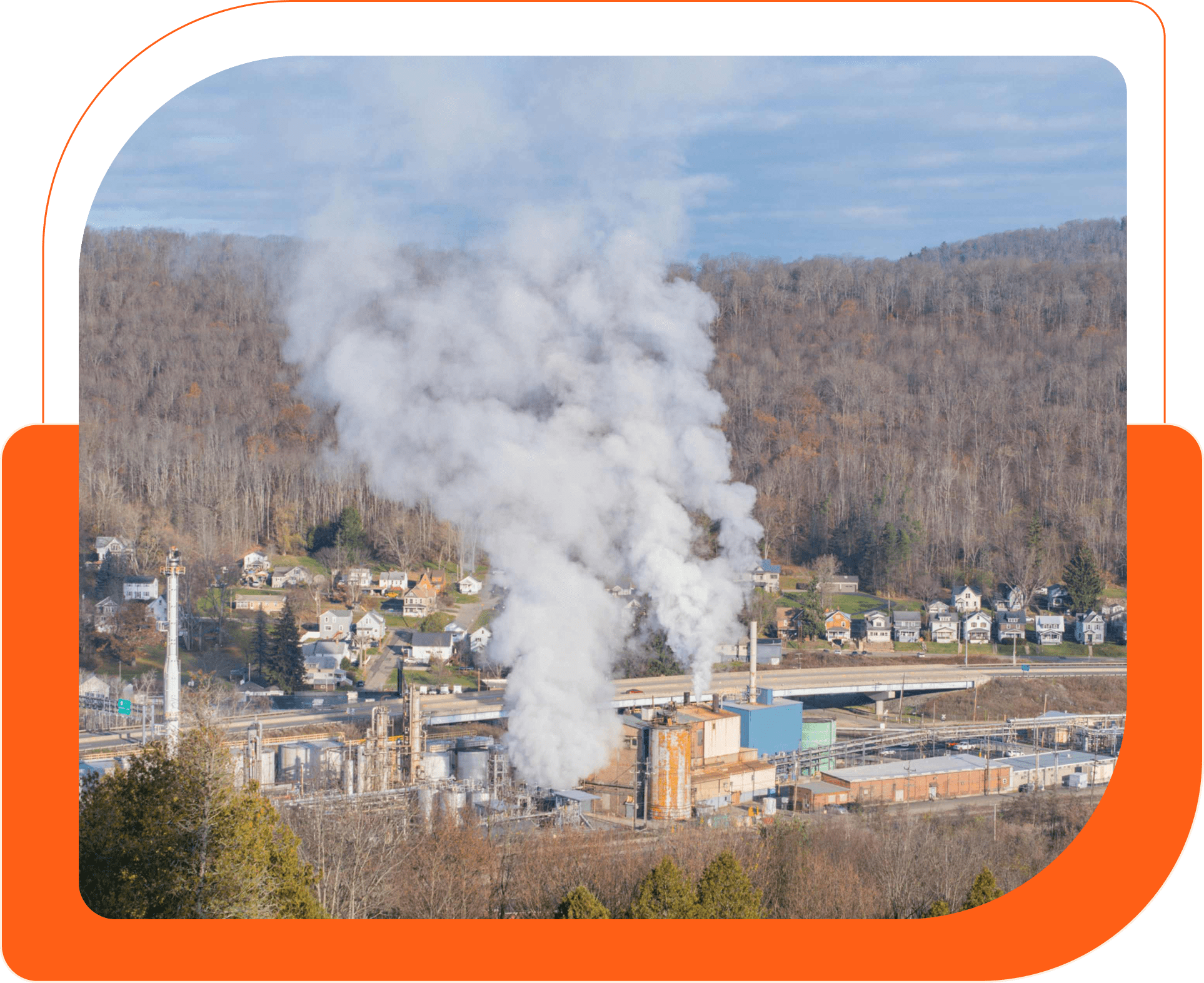 Industrial facility emitting smoke near forested area.
